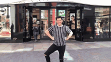 a man in a striped shirt stands in front of a store that has a sign that says ' christmas '