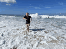 a man in a black shirt stands in the ocean