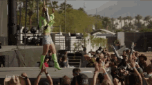 a woman in green boots is playing a guitar in front of a crowd with the words stage back on the bottom