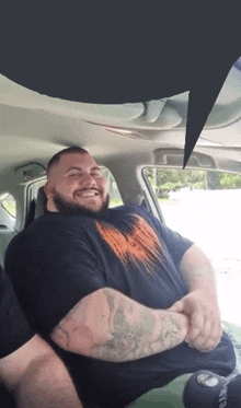 a man with a tattoo on his arm is sitting in the back seat of a car and smiling