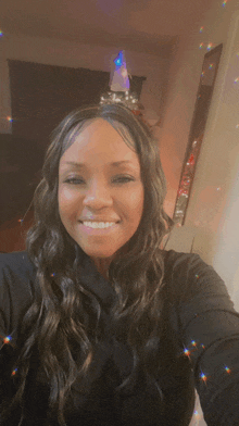 a woman in a black shirt smiles in front of a christmas tree