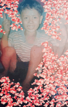 a young boy is smiling in front of a collage of pink hearts