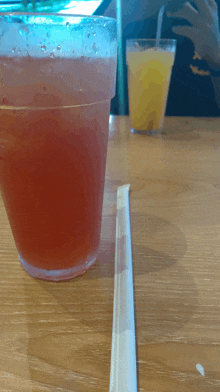 a glass of red liquid sits next to a straw on a table