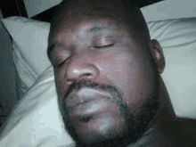 a man with a beard is sleeping on a pillow with his eyes closed .