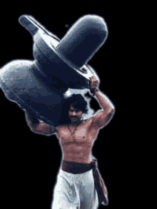 a man without a shirt is carrying a large stone on his shoulders