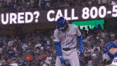 a baseball player in a new york jersey stands in front of a sign that says " cured call 800-5 "