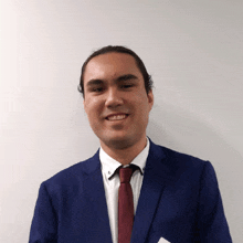 a man wearing a blue suit and a red tie smiles for the camera