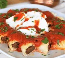 a white plate topped with meatballs , tomato sauce , sour cream and parsley .