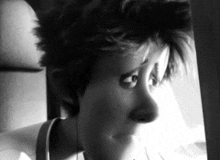 a black and white photo of a woman looking out of a window on a plane .