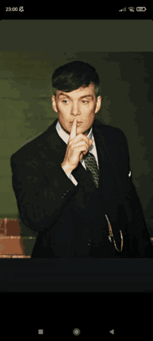 a man in a suit and tie is holding his finger to his lips