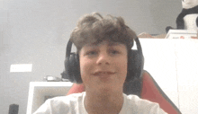 a young boy wearing headphones looks at the camera and smiles