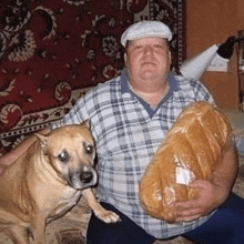 a man and a dog are posing for a picture while the man is holding a loaf of bread .