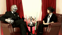 a man in a knight 's helmet sits next to a woman in a black chair