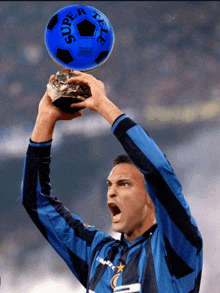 a soccer player holds a blue super tele soccer ball above his head