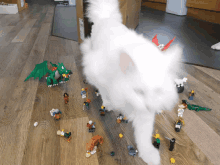 a white cat playing with a bunch of lego figures on the floor