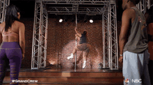 a woman on a pole is being watched by a man and a woman with the nbc logo on the bottom