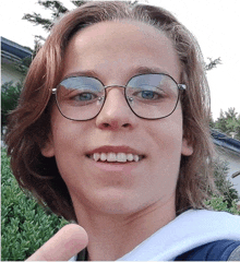 a young man wearing glasses is smiling and giving a thumbs up sign