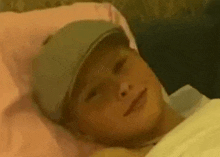 a young boy is laying in a bed wearing a hat .