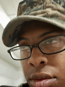 a man wearing glasses and a hat has a tear running down his cheek