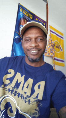 a man wearing a rams t-shirt and a hat smiles