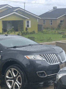 a black lincoln parked outside of a yellow house