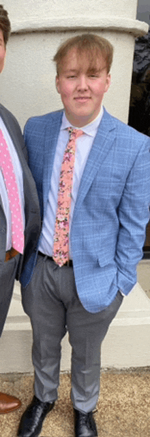 a young man wearing a blue suit and a pink tie