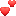 two red hearts are floating in the air on a white surface .