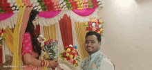 a bride and groom are posing for a picture in front of flowers .