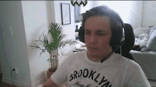 a man wearing headphones and a brooklyn new york shirt is sitting in a living room .