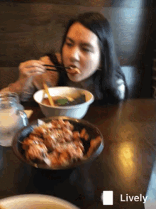 a woman sitting at a table eating a bowl of food with chopsticks and a lively icon in the corner