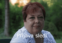 a woman with red hair is sitting in a chair in front of a forest .