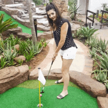 a woman is playing a game of golf on a course with the number 9 on the sign behind her