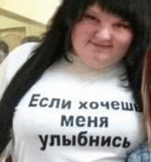 a woman wearing a t-shirt with russian writing on it is smiling .