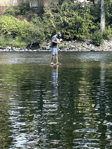 a man is standing in the middle of a river looking at something