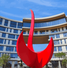 a red sculpture in front of a large building