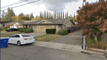 a white car is parked in front of a house with a garage