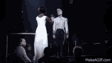 a man in a white dress is holding a woman in a white dress on stage .