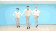 three young men in school uniforms are dancing in a room