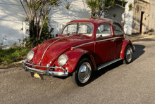 a red volkswagen beetle is parked in front of a garage