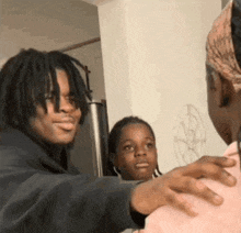 a man with dreadlocks is standing next to a woman and a girl .