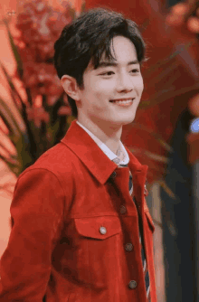 a young man wearing a red jacket and tie smiles