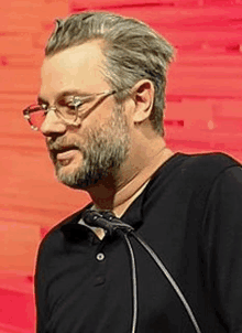 a man with a beard and glasses is standing in front of a podium .