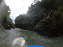 a group of people in yellow helmets are standing on a rock near a river