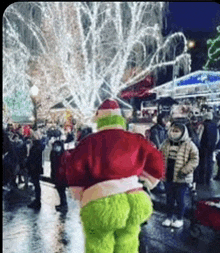 a grinch costume is standing in front of a crowd .