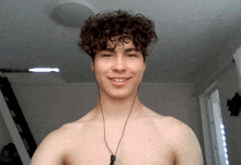 a shirtless man with curly hair wearing earbuds