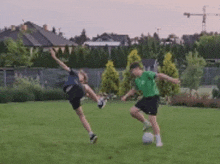 two children are playing soccer on a lush green field .