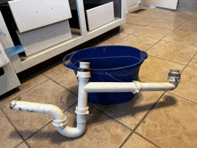 a blue bucket sits next to a pipe on the floor