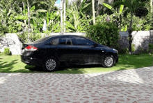 a black car is parked in a driveway surrounded by trees