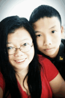 a boy and a woman are posing for a picture with the boy wearing a black shirt with a yellow letter l on it