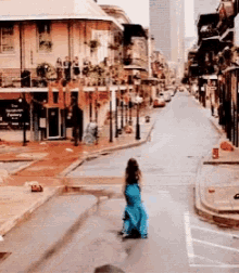 a woman in a blue dress is walking down a street in front of a building that says the french quarter